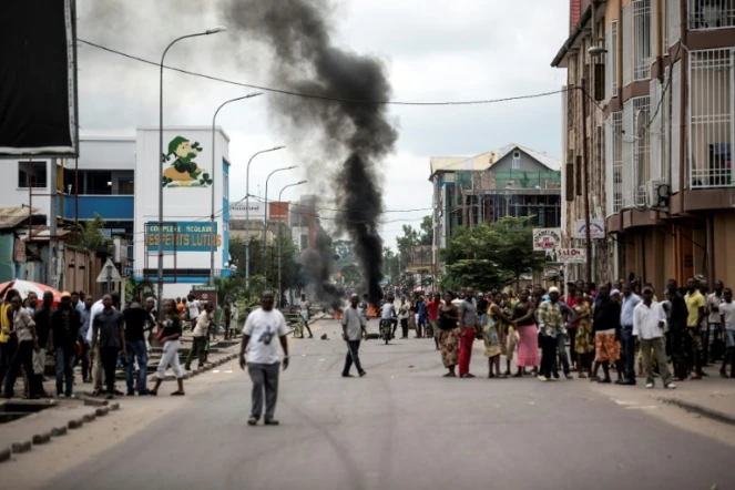 Des Kinois regardent des manifestants brûler des pneus au cours d'une marche anti-Kabila à Kinshasa, le 21 janvier 2018.
