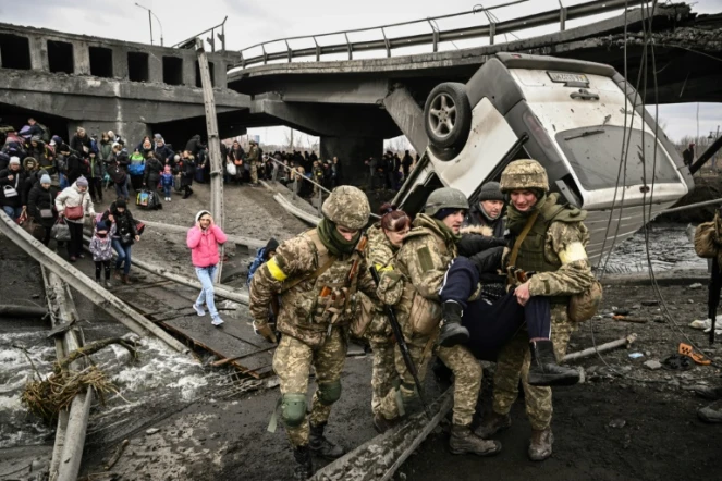 Des militaires ukrainiens aident des civils à évacuer la ville d'Irpin, au nord-ouest de Kiev, le 5 mars 2022