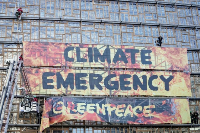 Des militants de Greenpeace évacués par des pompiers après avoir déployé une bannière sur le bâtiment du conseil européen à Bruxelles le 12 décembre 2019