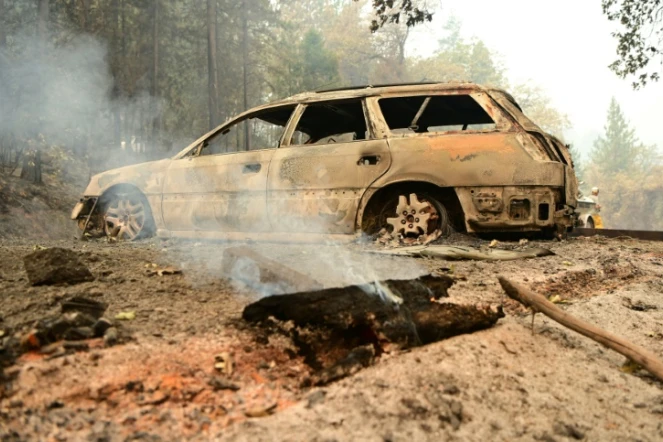 Un morceau de bois fume devant une voiture brûlée dans une propriété lors d'un incendie dans le comté de Shasta, au sud de Lakehead, en Californie, 2 juillet 2021