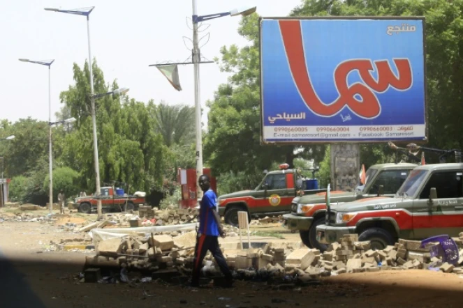 Un homme traverse une rue où sont postés des membres des Forces de soutien rapide (RSF), des paramilitaires accusés d'être à l'origine d'une vague de répression meurtrière, à Khartoum, le 10 juin 2019