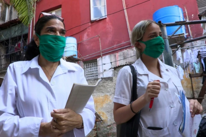 Liz Caballero Gonzalez (g), médecin, et l'étudiante en médecine Susana Diaz font du porte à porte dans le quartier du Vedado, le 31 mars 2020 à La Havane, pendant l'épidémie de coronavirus à Cuba