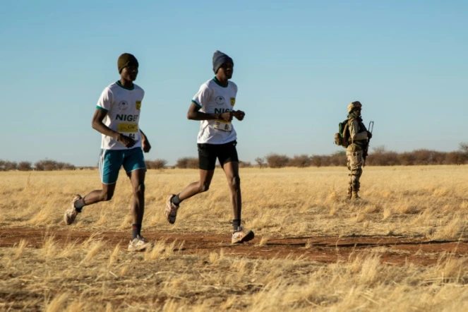 Deux marathoniens passent devant un soldat lors du premier marathon jamais organisé au Niger, le 29 décembre à Agadez.
