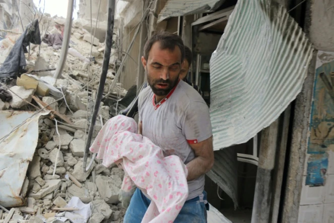 Un Syrien porte le corps d'un enfant mort dans un bombardement aérien, le 23 septembre 2016, dans le secteur al-Muasalat, à Alep