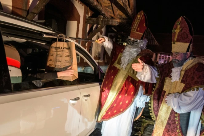 Des artistes du cirque Cirk La Putyka, déguisés en Saint Nicholas, distribuent des cadeaux aux enfants en voiture le 5 décembre 2020 à Prague