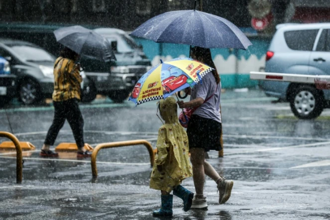 Des personnes tiennent des parapluies dans la rue sous la pluie à Keelung après le passage du typhon Haikui à Taïwan, le 4 septembre 2023 