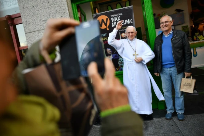 Des touristes se prennent en photo avec une statue de cire représentant le pape François à Dublin, le 24 août 2018