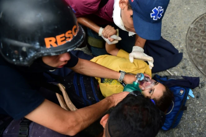 Des secouristes viennent en aide à une femme blessée lors des manifestations à Caracas le 20 avril 2017
