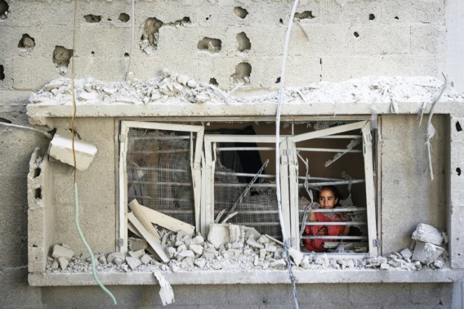 Un enfant palestinien regarde par la fenêtre d'un appartement endommagé par une frappe israélienne sur le camp de réfugiés de Nousseirat, dans le centre de la bande de Gaza, le 6 juillet 2024
