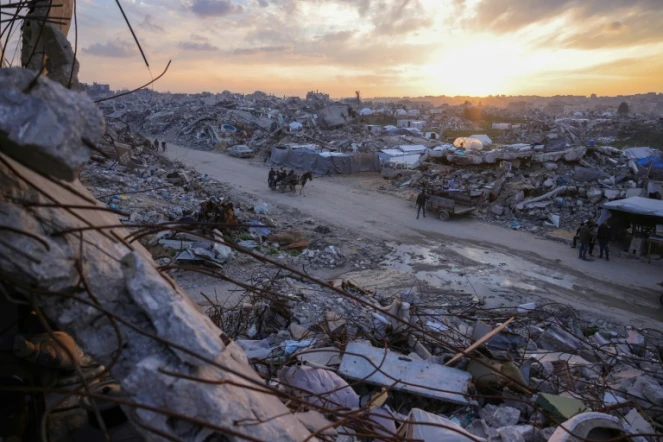 Des Palestiniens traversent à bord d'une charette une route au milieu des décombres à Beit Lahia, dans le nord de la bande de Gaza, le 4 mars 2025

