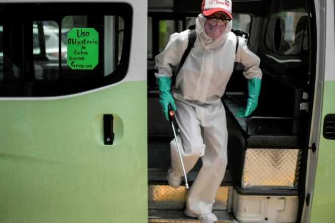 Un employé en équipement de protection désinfecte un autobus de transport en commun le 30 juillet 2020 à Mexico