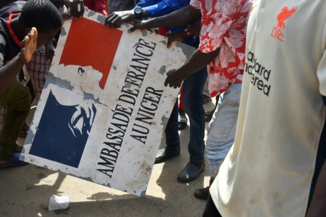 Des manifestants tiennent un panneau de l'ambassade de France après un rassemblement en soutien aux militaires putschistes au Niger, le 30 juillet 2023 à Niamey
