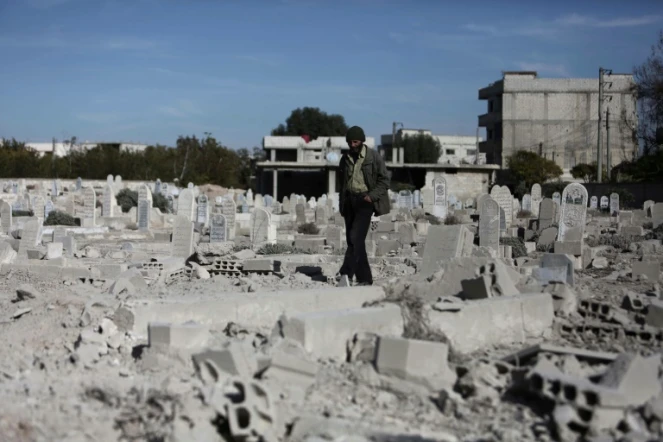 Un homme marche dans un cimetière détruit après des raids aériens dans le village de Deir al-Asafir dans la Goutha orientale, près de Damas, le 25 novembre 2015 