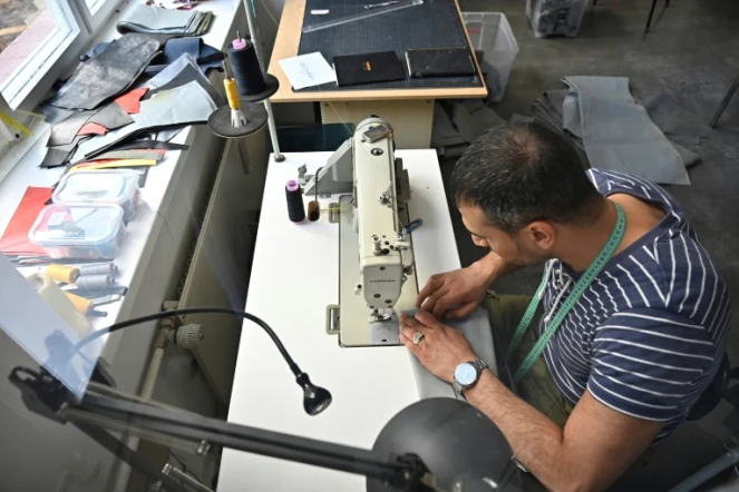 Penché sur sa machine à coudre, le Syrien Khaldoun Alhussain transforme un canot pneumatique en sac ou cabas, dans l'atelier de la petite entreprise mimycri à Berlin