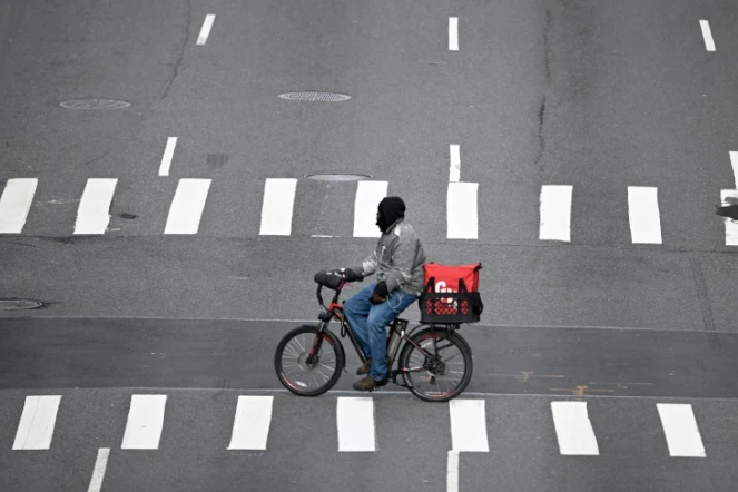 Un livreur à vélo traverse la 1re Avenue, désertée, le 17 mars 2020 à Manhattan
