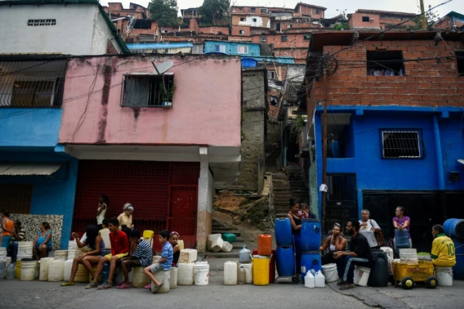 Des habitants du quartier de Petare font la queue avec des bidons et des seaux pour s'approvisionner en eau, le 1er avril 2019 à Caracas, au Venezuela