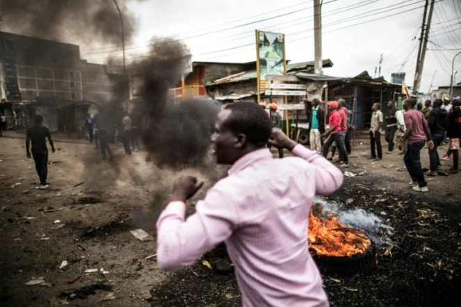 Des habitants marchent près de barricades en flammes dans le bidonville de Mathare à Nairobi, le 9 août 2017. Ils protestent contre les résultats de l'élection présidentielle au Kenya.