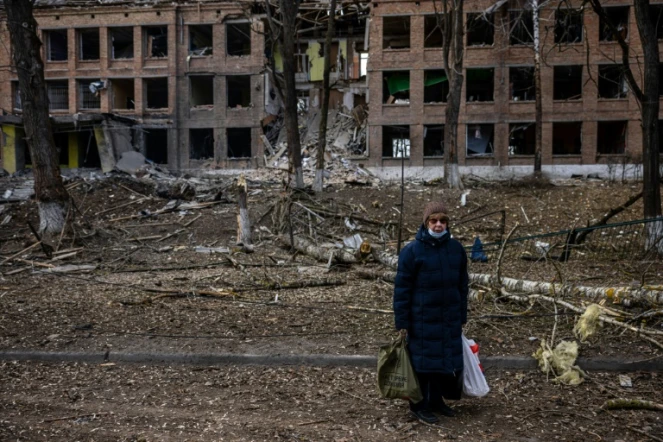 Une femme se tient devant un immeuble détruit après une attaque des forces russes dans la localité ukrainienne de Vasylkiv, près de Kiev, le 27 février 2022