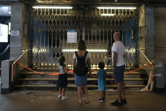 Une famille devant les grilles fermant l'accès à une station de métro dans le quartier d'Admiralty, le 6 octobre 2019 à Hong Kong