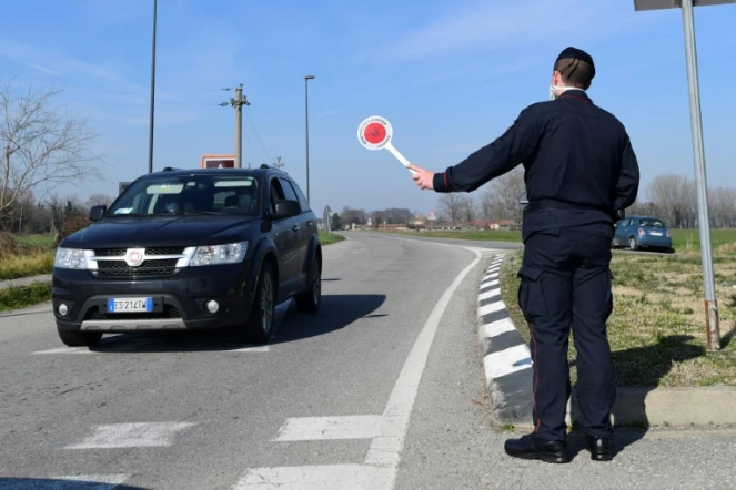 Un policier italien stoppe une voiture à un point de contrôle près de la petite ville de Castiglione d'Adda, au sud-est de Milan, le 24 février 2020.  