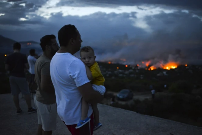 Des Grecs observent un feu de forêt à Rafina dans la banlieue d'Athènes, en Grèce