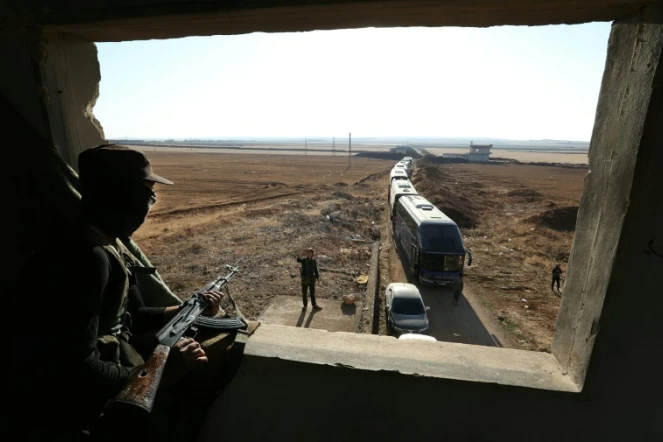 Un membre du groupe jihadiste Hayat Tahrir al-Sham observe un convoi de bus se préparant à évacuer les villes de Foua et Kefraya en Syrie