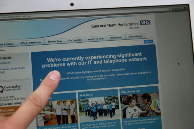 Une femme montre le site Web du NHS (East and North Hertfordshire), informant les utilisateurs d'un problème dans son réseau, à Londres le 12 mai 2017