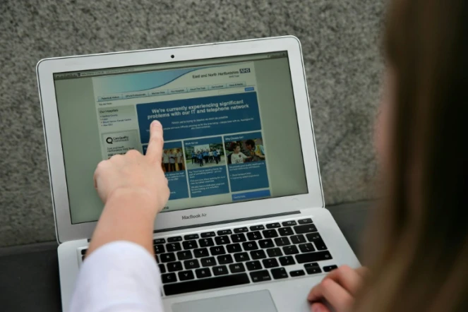 Une femme montre le site Web du NHS (East and North Hertfordshire), informant les utilisateurs d'un problème dans son réseau, à Londres le 12 mai 2017