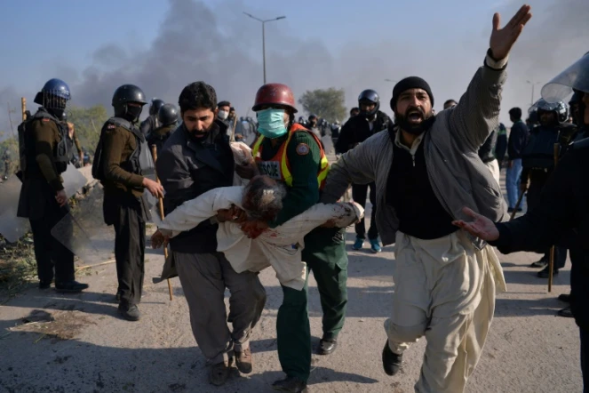 Des manifestants islamistes pakistanais évacuent l'un des leurs blessé lors d'affrontements avec la police samedi 25 novembre 2017 à Islamabad