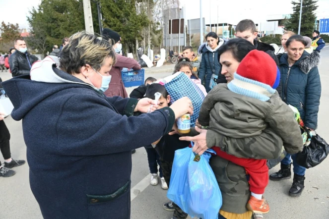 Une femme donne de la nourriture à une réfugiée ukrainienne et son enfant, à Tiszabecs (Hongrie), le 27 février 2022