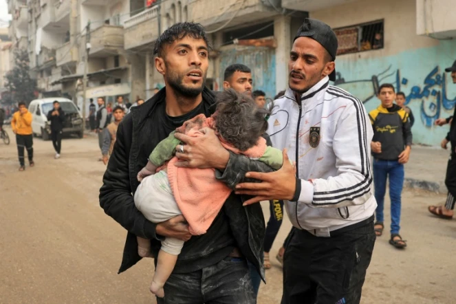 Un homme porte un enfant blessé lors d'un bombardement israélien, le 14 décembre 2023 à Rafah dans la bande de Gaza