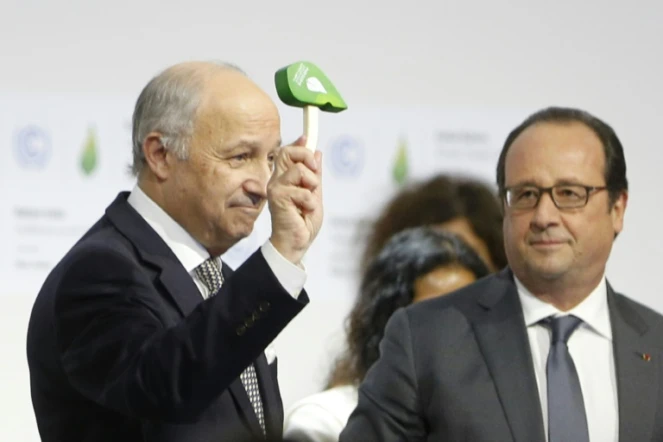 Le ministre des Affaires étrangères français, Laurent Fabius (g) brandit son petit marteau vert, sous le regard du président François Hollande, à Paris le 12 décembre 2015