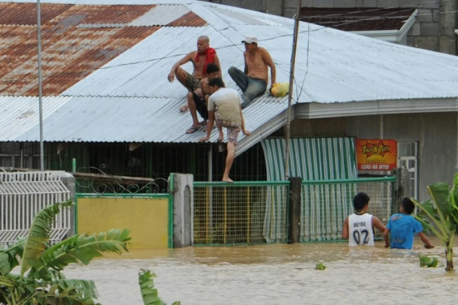 Des habitants trouvent refuge sur le toit de leur maison, le 19 octobre 2015 lors du passage du typhon Koppu sur la ville de Santa Rosa, au nord de Manille 