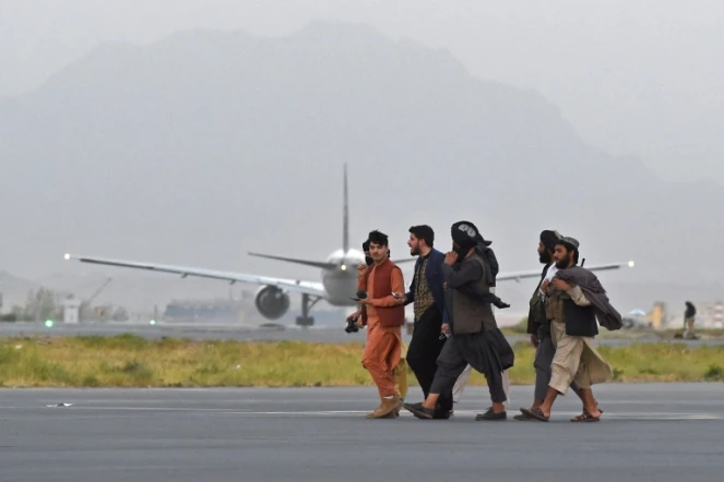 Des combattants talibans passent près d'un avion de Qatar Airways qui doit effectuer un nouveau vol d'évacuation depuis l'aéroport de Kaboul le 10 septembre 2021