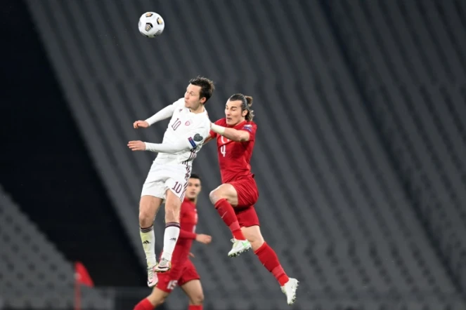 Le Letton Janis Ikaunieks (g) à la lutte avec le Turc Caglar Soyuncu, lors de leur match de qualification pour le Mondial-2022, le 30 mars 2021 à Istanbul