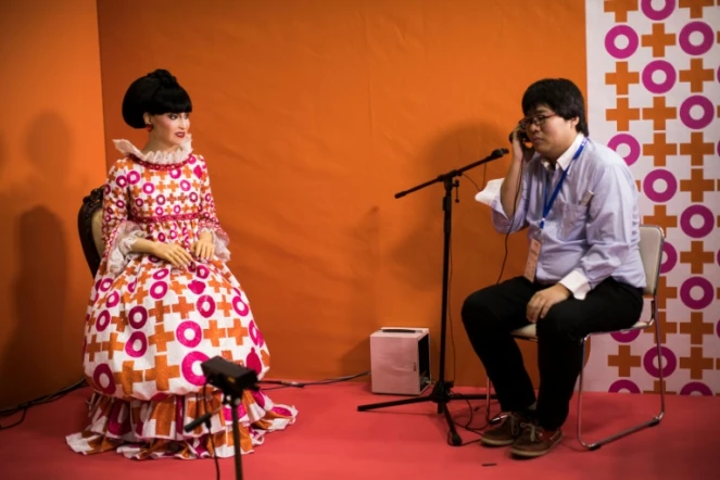 Un homme parle avec le robot androïd "totto", réplique quasi parfaite de la star de la télé japonaise Tetsuko Kuroyanagi, au salon World Robot Summit, le 18 octobre 2018 à Tokyo