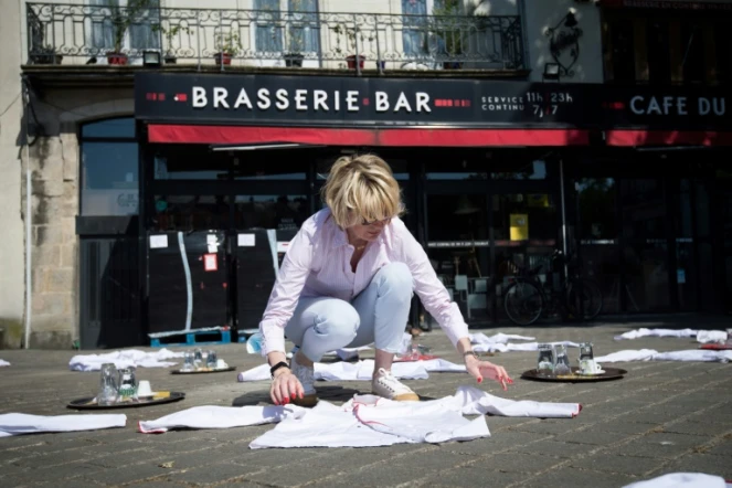 Une femme étale des dizaines de blouses blanches, toques et plateaux sur une place face à un restaurant à Nantes, ouest, le 27 mai 2020, pour protester contre les conséquences du confinement 