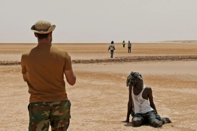 Un garde-frontière libyen observe des migrants africains dans le désert, près d' Al'Assah, à la frontière entre la Libye et la Tunisie, le 30 juillet 2023