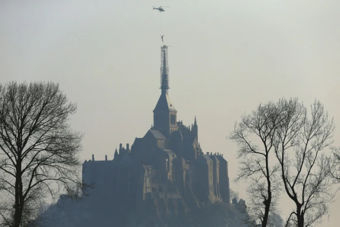 Un hélicoptère hélitreuille la statue de l'archange qui domine l'abbaye du Mont Saint-Michel, le 15 mars 2016