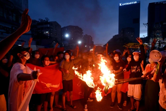 Des protestataires brûlent des drapeaux birmans lors d'une manifestation contre la junte à Rangoun le 29 juillet 2021