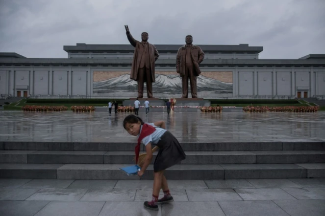 Une écolière nettoie le parvis devant les statues des leaders nord-coréens Kim Il-Sung (g) et Kim Jong-Il (d), le 27 juillet 2017 à Pyongyang