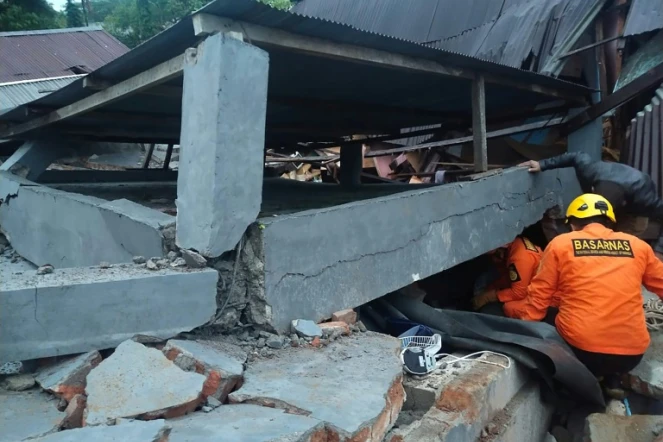 Les secours indonésiens fouillent les décombres d'un bâtiment effondré à Mamuju, sur l'île des Célèbes, frappée par un puissant séisme le 15 janvier 2021