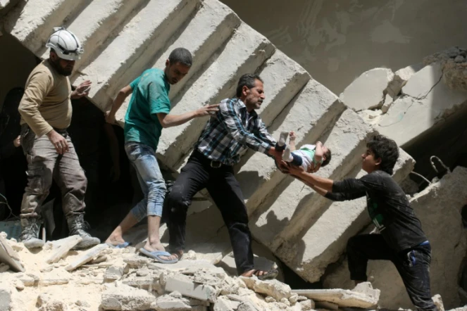 Des volontaires de la Défense civile syrienne, sortent un enfant des décombres d'un immeuble bombardé à Alep le 28 avril 2016