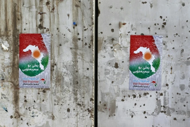 Des affiches encourageants les citoyens à voter au référendum sur l'indépendance du Kurdistan, collées sur un mur criblé de balles à Kirkouk, le 24 septembre 2017