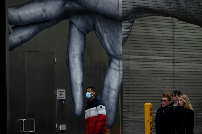 Un homme marche devant une fresque murale à New York, le 14 mars 2020