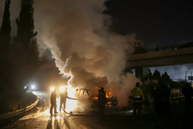 Des pompiers éteignent un véhicule de la Finul, incendié par des manifestants, sur la route menant à l'aéroport de Beyrouth, le 14 février 2025 au Liban