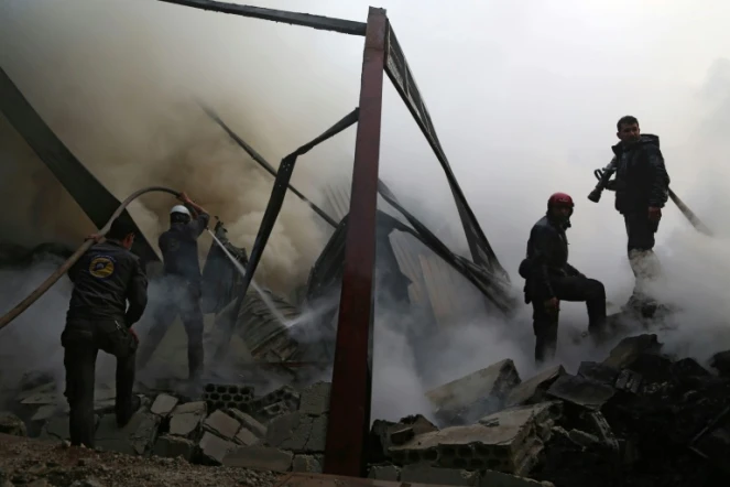 Des Casques blancs syriens éteignent un incendie provoqué par des frappes aériennes du régime sur la ville rebelle de Hamouria, dans les environs de Damas, le 21 mars 2017