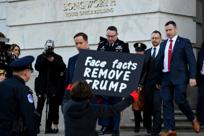 Une manifestante en faveur de la destitution de Donald Trump tient une pancarte à la sortie du  lieutenant-colonel Alexander Vindman, témoin dans l'enquête visant le président américain, le 19 novembre 2019