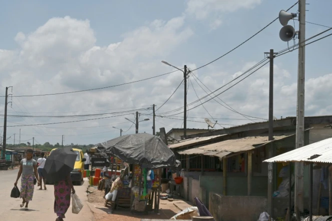 Des habitants font leurs courses dans une rue du village d'Azaguié Ahoua, près d'Abidjan, où des hauts-parleurs diffusent des messages sur le coronavirus, le 27 mars 2020 en Côte d'Ivoire