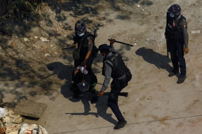 Des policiers frappent un protestataire lors d'une manifestation pro-démocratie à Rangoun, le 6 mars 2021